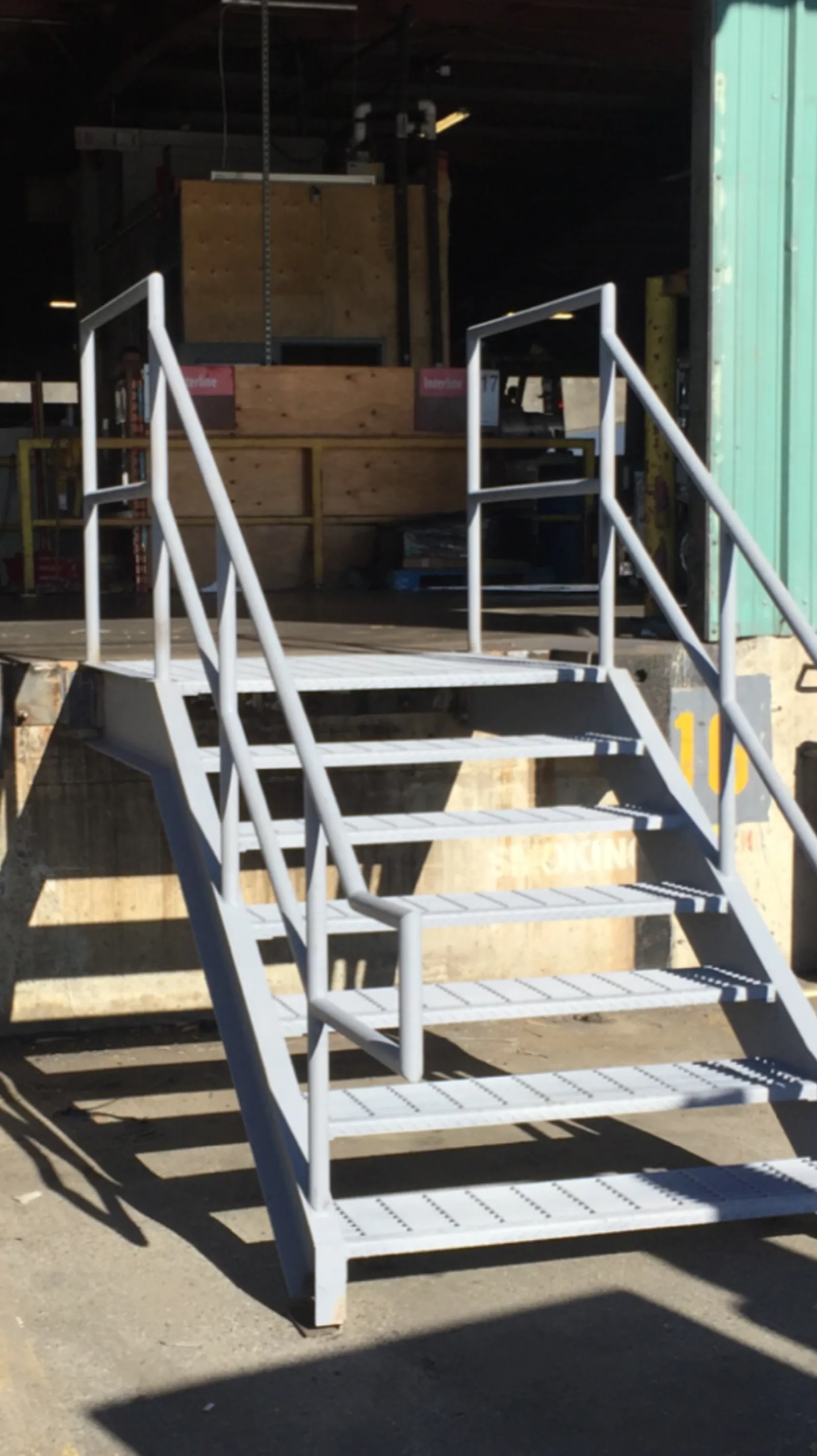 New warehouse access stair in our shop with double stringers, bar grating treads, and tubular pipe-rail guards before paint, the standard detail we ship for exterior commercial use