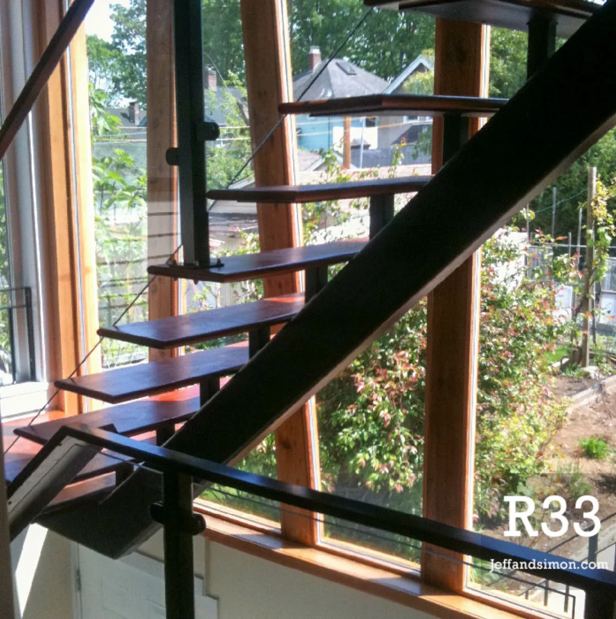 Mono stringer staircase with cable railing and wood treads beside bay window, Vancouver